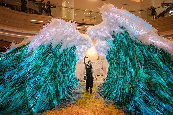 man taking selfie next to largest drinking straw sculpture
