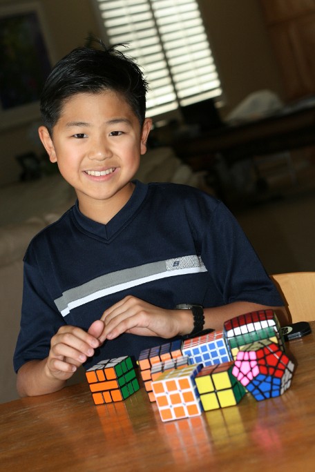 max park as a young child smiling next to his rubiks cubes
