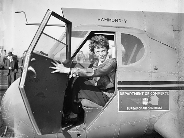 amelia earheart smiling as she holds open plane door