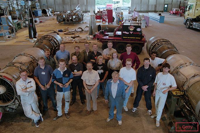 The Thrust SSC engineering team pose between the car’s two massive jet engines