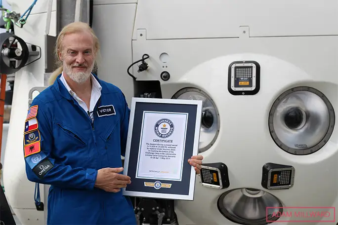Victor beside the Limiting Factor sub, holding one of his Guinness World Records certificates and the GWR 2021 book in which he features